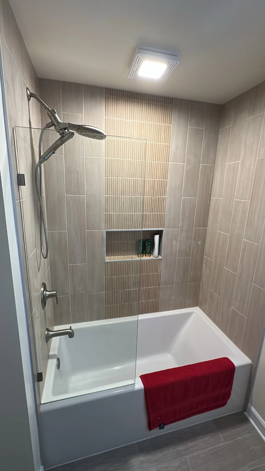 Tiled bathtub surround with vertical accent tile, recessed niche and glass screen