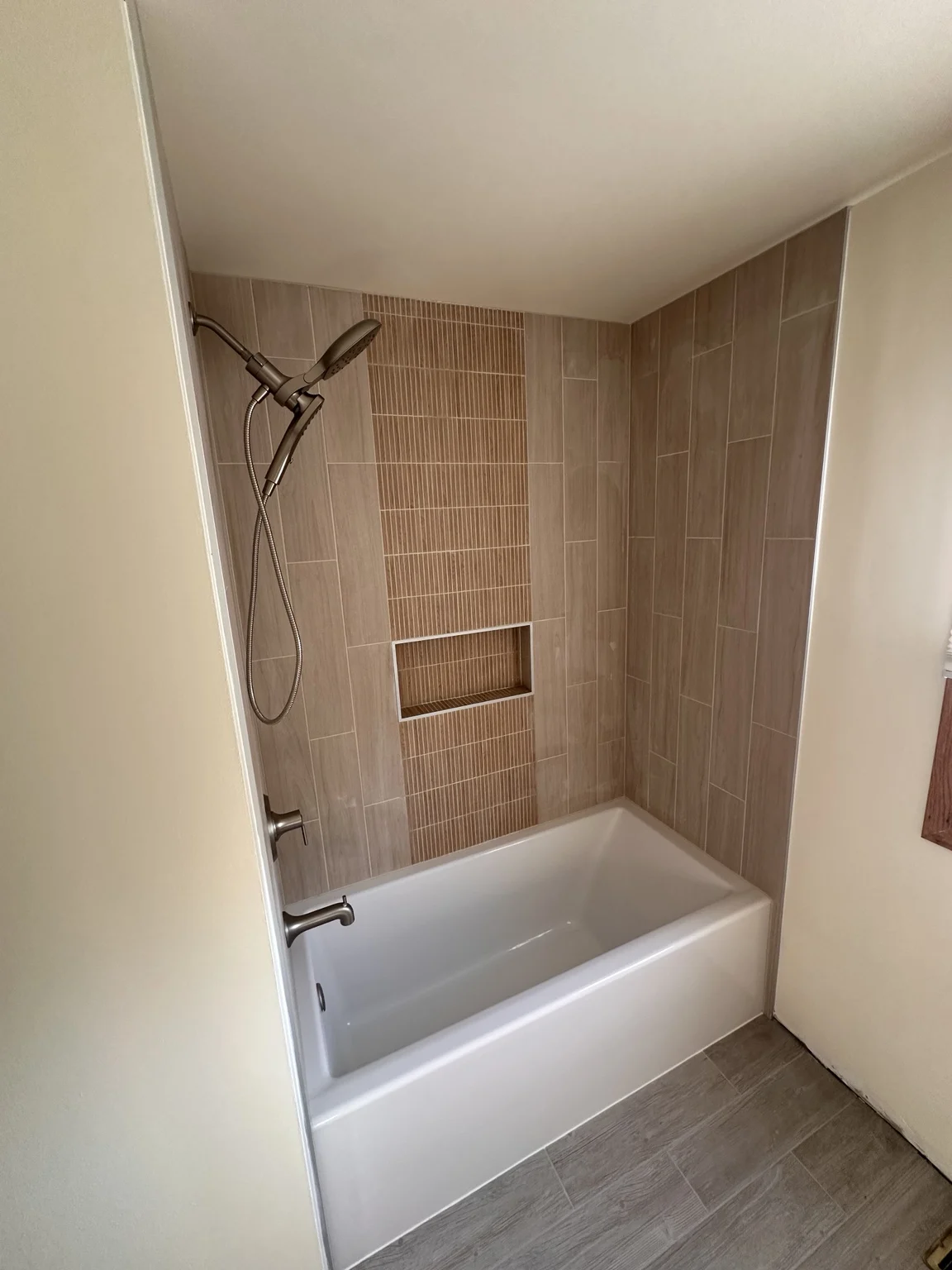 Bathtub with vertical wall tile and contrasting accent strip around a recessed niche