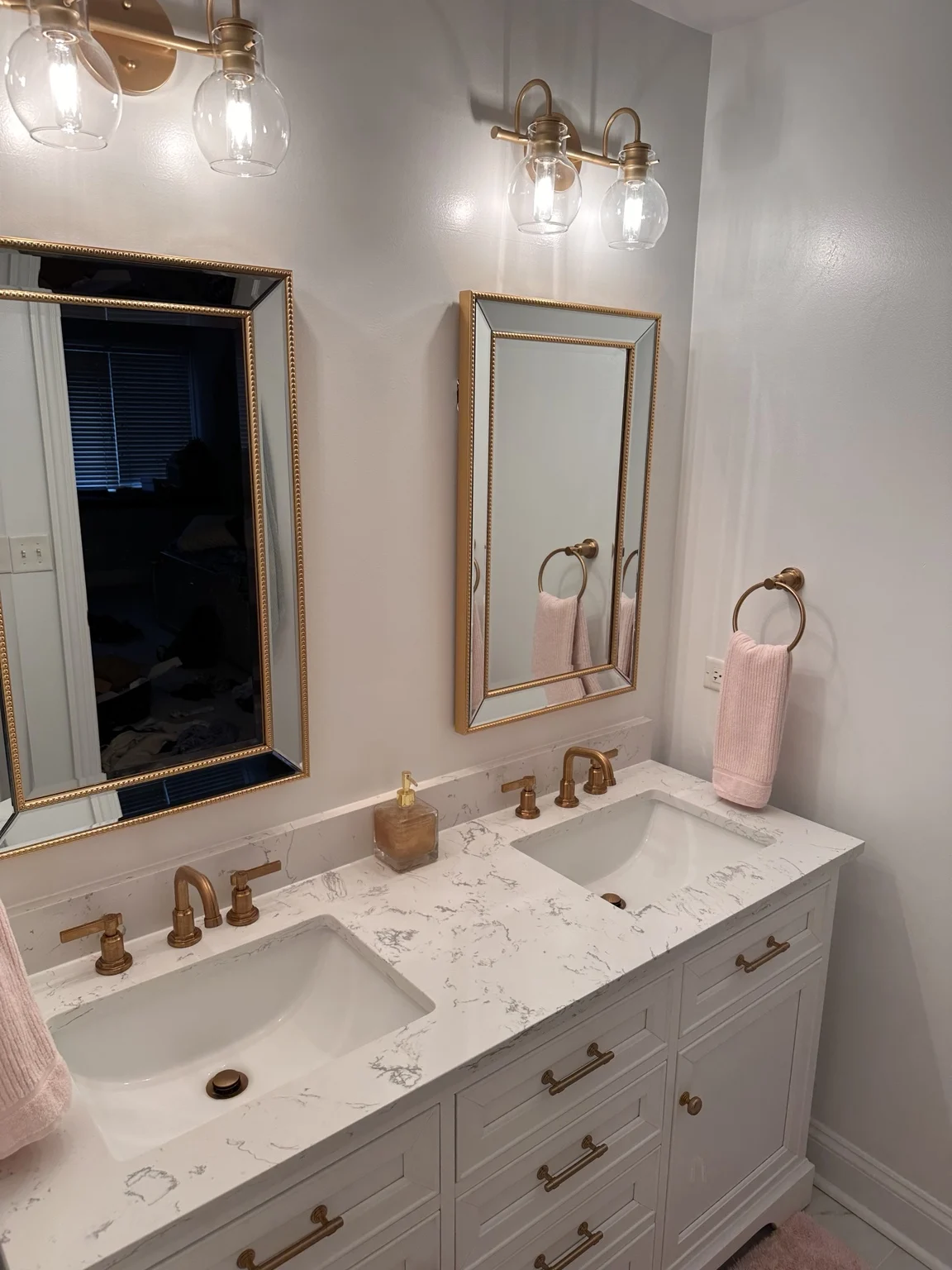 White double vanity with gold-toned faucets, framed mirrors and matching lights