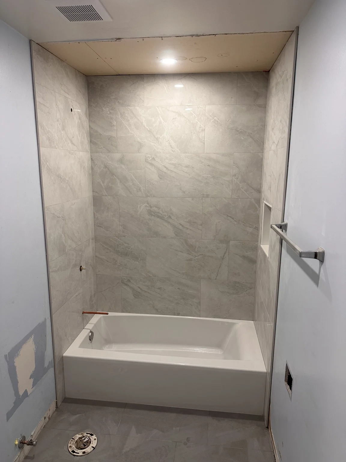 Front view of large-format tiled bathtub surround during bathroom renovation